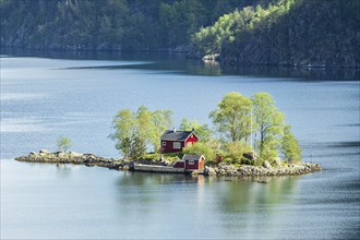 Typical red norwegian cottage on a little island in the fjord, Lovrafjord, Norway, Europe