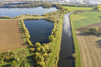 River Leine meanders through farmland and meadows, sugar factory of company Nordzucker in the back,