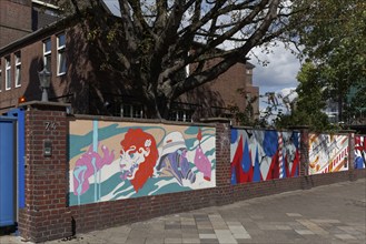 A row of colourful paintings on an old brick wall, decorative street art commissioned by the city