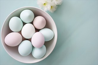 Bowl with pastel colored Easter eggs on blue background with copy space. KI generiert, generiert AI