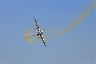 Stunt aerobatic plane performing stunts in blue sky with smoke trail. Concept of speed, difficulty,