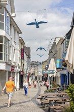 Lively shopping street with blue bird sculptures above the heads of passers-by, Waterford