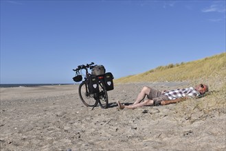 Senior takes a break by bike on the beach in Denmark