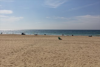 Wide expanse of sand in front of a calm blue sea and clear sky, Cadiz