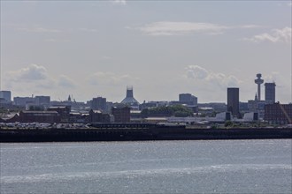 Distant view of Liverpool showing modern and historic buildings surrounded by haze and clouds,