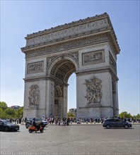 The Arc de Triomphe in Paris in sunny weather, surrounded by people and cars, Paris