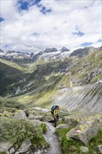 Mountaineer on a hiking trail in front of a picturesque mountain landscape, rocky mountain peaks