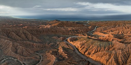 Riverbed runs through a landscape of eroded hills, badlands at sunset, Issyk Kul Lake in the