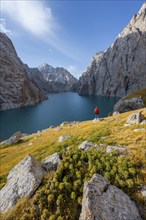 Tourist at the blue mountain lake between rocky steep mountain peaks, Kol Suu Lake, Sary Beles