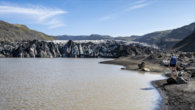 Tourist on the shore of a glacier lagoon, glacier tongue and lake, Sólheimajökull, South Iceland,