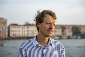 Young man in striped shirt, portrait, on the banks of the Grand Canal, Venice, Veneto, Italy,