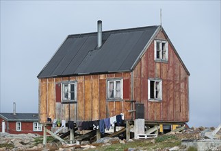 Small red house, clothesline with hanging laundry, remote Arctic Inuit settlement Ittoqqortoormiit,