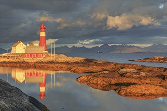 Lighthouse reflected in water, morning light, clouds, mountains, coast, Tranoy, Ofoten, Norway,