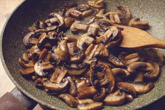 Fried mushrooms in a frying pan, with a wooden fork, homemade, no people