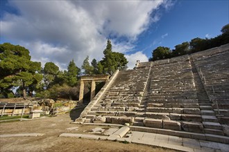 Partially restored amphitheatre under a blue sky next to green vegetation, Ancient Amphitheatre,