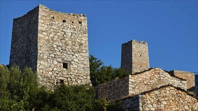 Ancient stone towers rise under a clear blue sky, Lagia, residential towers village, Mani