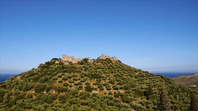 Medieval fortress on a wooded hill under a bright blue sky, Mani Peninsula, Peloponnese, Greece,