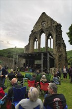 Visitors at an open-air concert in the evening, ruin, Abbey Farm, Llangollen, North Wales, Wales,