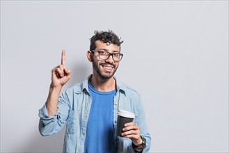 Young man with paper coffee cup pointing finger up, Happy smiling person with paper coffee cup