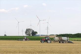 Farmers spread liquid manure on harvested grain field and plough it up, wind farm, Swabian Alb,