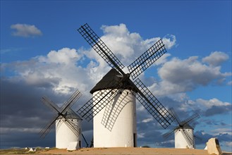 Three windmills stand in an open landscape under a cloudy but sunny sky, Windmills, Campo de