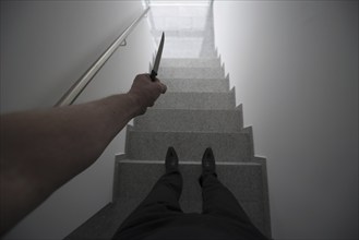 Personal Perspective on a Violent Man Holding a Knife in a Staircase with a Window Light in