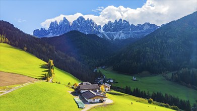 Farm and alpine meadows, in the background the peaks of the Geisler group, drone shot, Sankt