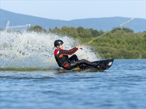 Young man doing sports with wakeboard in lake, water sports, water skiing in wakepark, Stráž pod