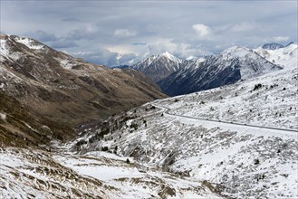 Schneebedeckte Berge und ein kurvenreiches Tal in Andorra, durchzogen von einer Straße, nördlich