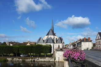 Kirche in einem kleinen Dorf mit klarblauem Himmel und grünen Bäumen, Blumen auf einer Brücke und