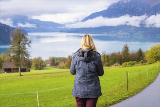 Woman looking at a calm lake, framed by mountains and clouds, Lake Brienz, Switzerland, Europe