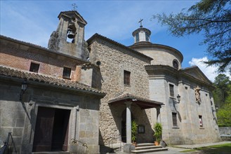 Stone church with bell tower and cross, surrounded by nature and under a blue sky, Santuario de San