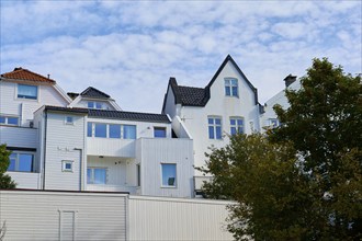 Building with white facade and white window frames under a blue sky with light sky, Bergen,