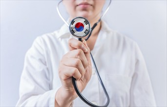 Female doctor holding stethoscope with South Korean flag. South Korean Health and Care concept