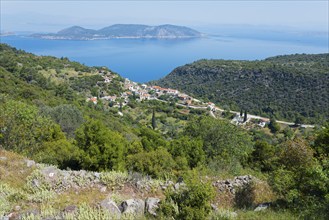 Coastal landscape with a village surrounded by green hills and the blue sea in the background,