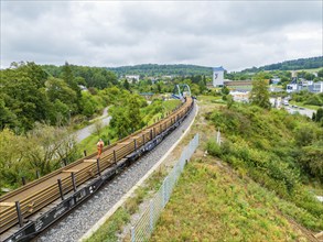 Train on railway line next to green countryside and city view, track construction, rail delivery