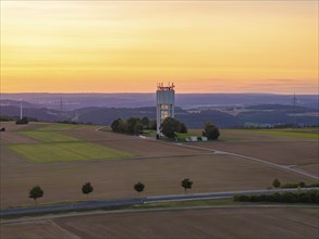 Hilly landscape with fields and a tower in the sunset light, Jettingen, Black Forest, Germany,