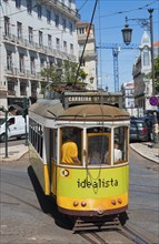 Yellow-green tram bends around a curve through the city, Tram, Line 28, Carros eléctricos de