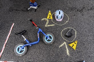 Markings at an accident scene with a balance bike for children, helmet, reenacted accident