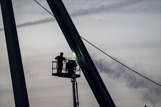 Worker cleans a bridge pier with a high-pressure cleaner on a cherry picker at the Erasmus Bridge