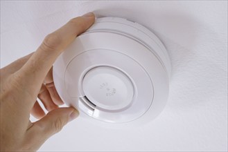 Symbolic photo on the subject of smoke alarms. A smoke detector hanging from the ceiling in a flat.