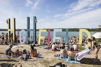 Festival visitors in front of a Highfield lettering on the beach at the Highfield Festival on