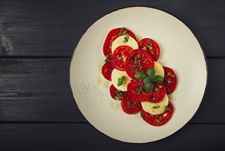 Caprese salad, Italian traditional dish, tomatoes with mozzarella cheese, basil and spices, top