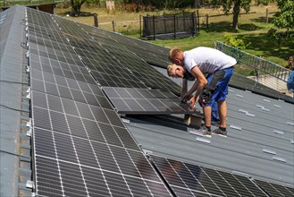 Installation of solar modules on the roof of a barn on a farm, over 210 photovoltaic modules are