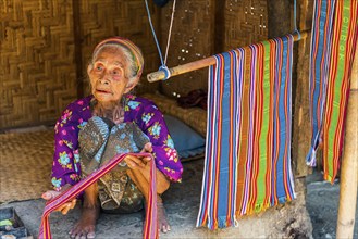 Old woman offering textiles for sale, textile, old age, human, work, colourful, clothing, village,