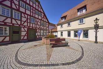 Running fountain with bench and sports shop on the alleyway Große Gasse in Michelstadt, Odenwald,