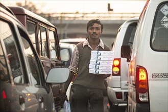 Street vendor standing between waiting cars, New Delhi or New Delhi, India, Asia