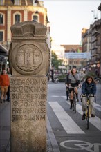 Historical stone with kilometre markers shows distances, cyclists, Nørreport, Copenhagen, Denmark,