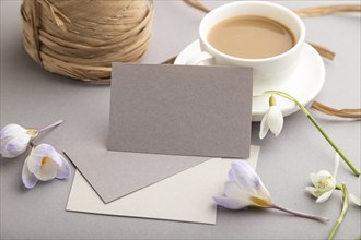 Gray paper business card mockup with spring snowdrop crocus and galanthus flowers and cup of coffee