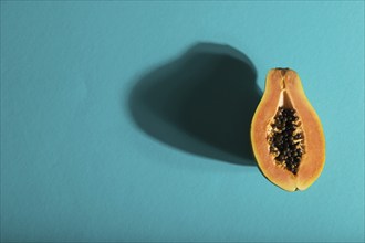 Ripe cut papaya on blue pastel background. Top view, flat lay, copy space, hard light. Tropical,